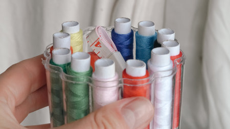 Colorful sewing threads, safety pins, and tape measure on white background.の写真素材