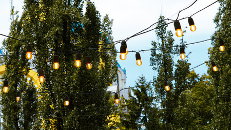 Warm glowing garland lights decorating outdoor seating area in city cafe.の写真素材
