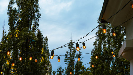 Outdoor string lights hanging in cozy city cafe setting at dusk ambiance.