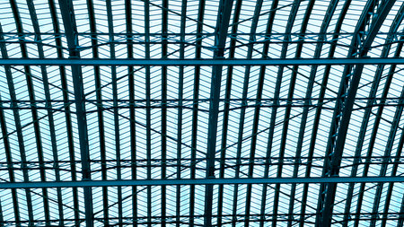 Symmetrical industrial ceiling pattern showing steel beams and glass light.の写真素材