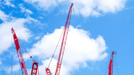 Construction crane structure reaching high in the sky on clear sunny dayの写真素材