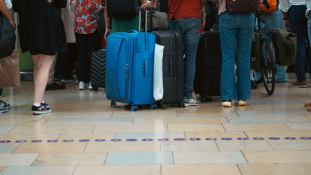 Group of travelers with suitcases walking on train platform during relocation.