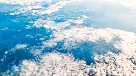 Bright daylight clouds beneath floating aircraft wing in calm clear blue sky.