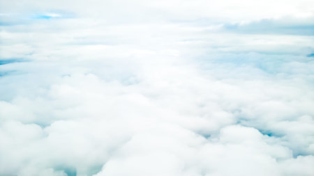 Soft cloudscape from airplane window with peaceful blue sky and sunlight glow