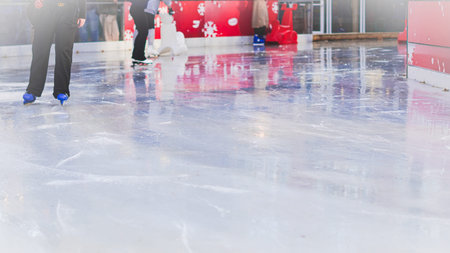 Skaters feet gliding on ice at Christmas fair with bright festive lights