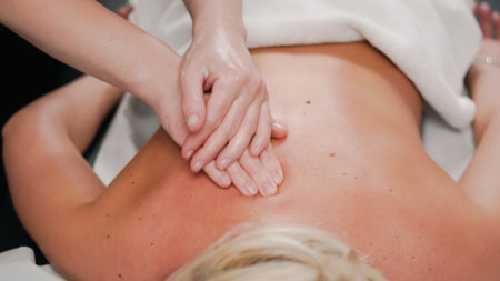Gentle massage hands working on blonde client creating calm salon atmosphere.の写真素材