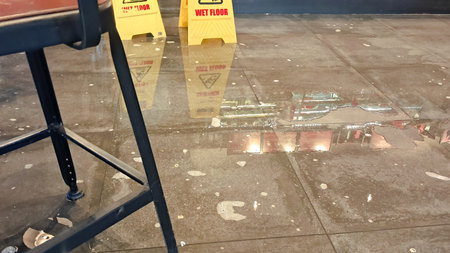 Water leaking across cafe floor after toilet malfunction with wet floor signs