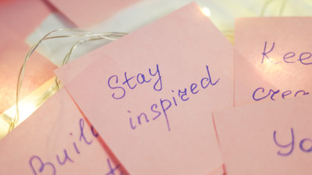 Colorful sticky notes with handwritten motivational phrases and fairy lights on a table