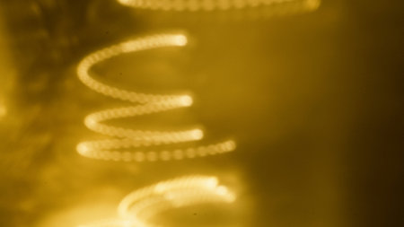 Close-up of abstract light patterns in golden tones featuring swirling shapes and reflectionsの写真素材