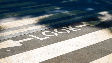 Look sign painted on a pedestrian crosswalk with white stripes and shadows from treesの写真素材