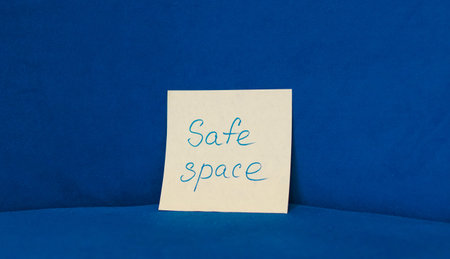 A sticky note displaying the words Safe space on a blue background with soft texture