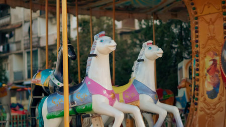 Three decorative carousel horses with vibrant colors on a ride in an amusement parkの写真素材