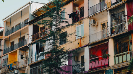 Multi-story apartment building featuring balconies and greenery in an urban environmentの写真素材