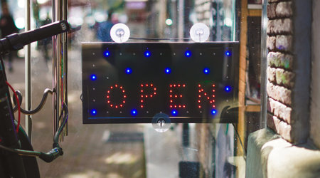 Bright LED open sign with red and blue lights visible in a shop window