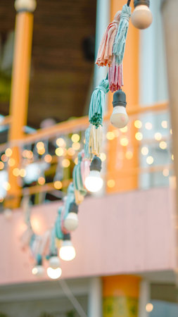 Colorful tassels and glowing bulbs of decorative string lights are visible outdoors at night