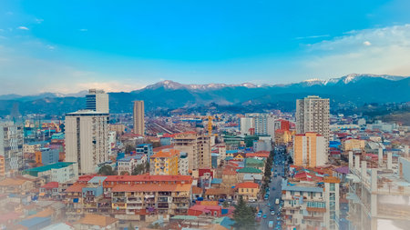Aerial perspective of a vibrant city with colorful buildings and snow-capped mountains visible