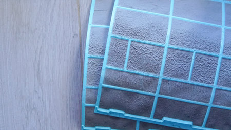 Air conditioning filter with a blue frame placed on a light wooden surface