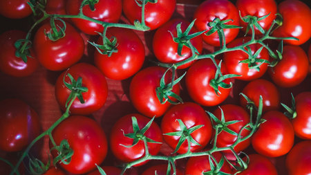 Ripe red tomatoes with green stems placed closely in a wooden crate for visual appeal