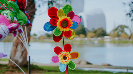 Brightly colored flowers stand near a lake with balloons visible in the background