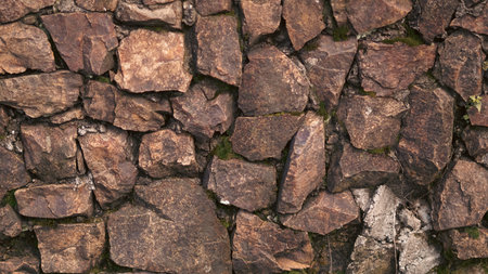 Close-up view of a stone wall featuring various sizes of rocks and patches of moss