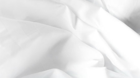 Close-up of white fabric displaying soft folds and creases suitable for background useの写真素材