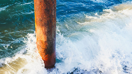 Weathered wooden post stands in ocean water with waves crashing against it