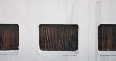 Three windows with brown curtains are set in a white wall, showcasing a simple design