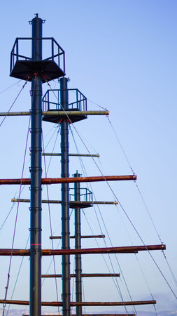 Three tall metal masts with platforms and rigging against a clear blue sky