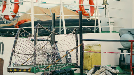 Fishing boat deck featuring safety equipment, nets, and ropes in a harbor environment