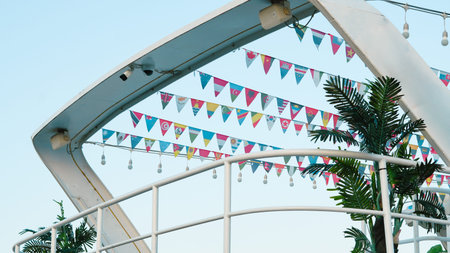 Decorative flags in various colors hang above a white railing with green plants visible