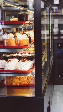 Assorted gourmet cakes and pastries on shelves in a bakery display case
