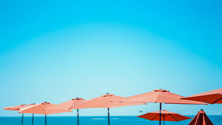 Orange beach umbrellas against a vibrant blue sky and sea