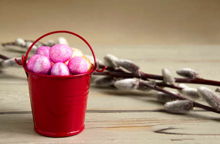 Easter shiny eggs in a bucket on a wooden backgroundの写真素材