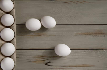 White eggs in a cardboard box on a wooden background