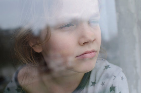 A thoughtful girl looks out the window.