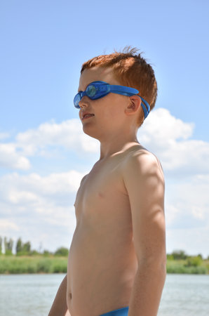 A boy with red hair looks forward in swimming gogglesの写真素材