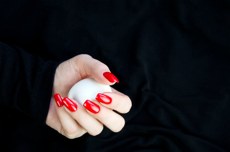 A woman's hand holding an egg on a black backgroundの写真素材