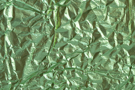 Textured background made of shiny green sheet foil.の写真素材