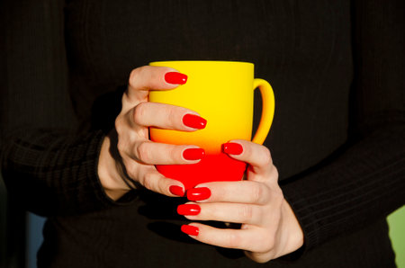 Female hands holding mugs with coffeeの写真素材