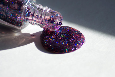 Glitter nail polish pouring from a bottle onto a surfaceの写真素材