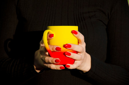 Female hands holding mugs with coffeeの写真素材