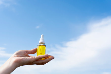 Cosmetic oil with a pipette in female hands on a blue backgroundの写真素材