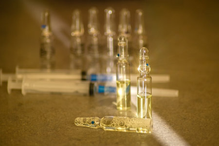 Glass ampoules with yellow medicine and syringes lie on the tableの写真素材