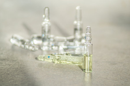 Glass ampoules with yellow medicine are on the tableの写真素材