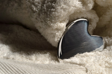 Stainless steel gua sha tool with soft towel, close-upの写真素材