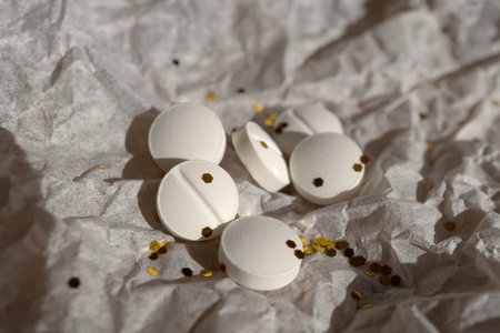 White pills and glitter lie on white packaging paper. Party concept