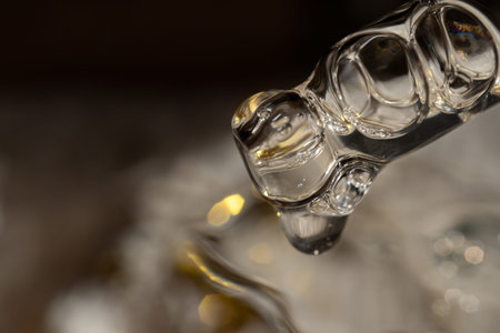 Pipette with cosmetic product on blurred holiday background with bokehの写真素材