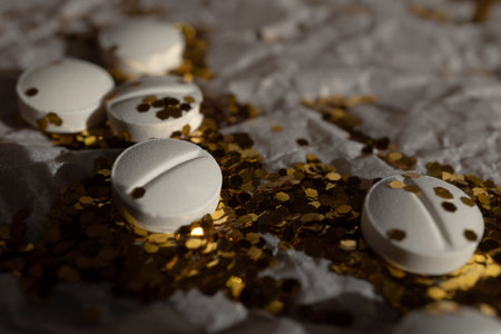 White pills and glitter lie on white packaging paper.の写真素材