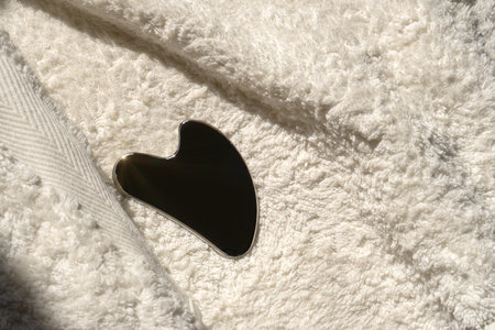 Stainless steel gua sha tool with soft towel, close-upの写真素材