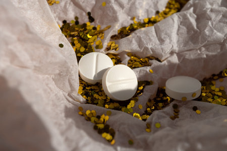 White pills and glitter lie on white packaging paper. Party concept